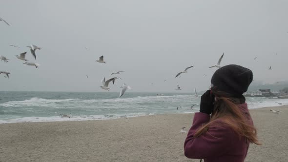 Woman Speaks on the Phone and Pulls Her Hand Towards the Birds