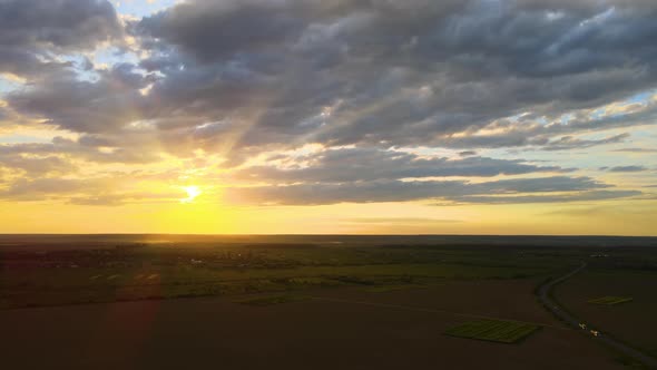 Aerial View of Intercity Road with Fast Driving Cars Between Farmland Fields at Sunset alt