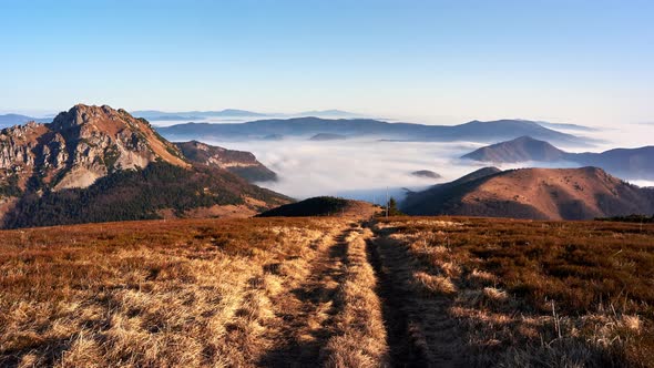 The rocky peak of the mountain is surrounded by low inverse clouds. Flying parachutist