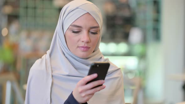 Portrait of Focused Young Arab Woman Using Smartphone  alt