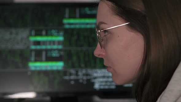 Hacker tries to hack into the system. A female hacker works at a computer at night in the dark. alt