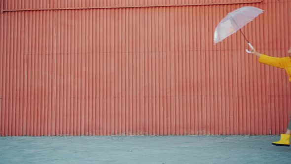 Slow Motion of Happy Girls Friends in Raincoats Running Outdoors with Umbrella alt