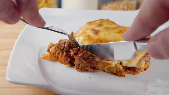Close Slow Motion Slider Shot of Eating a Fresh Portion of Lasagne on a White Plate with a Knife and alt