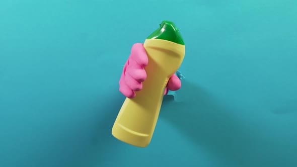 In the Torn Hole a Hand in a Glove Holds a Yellow Bottle of Household Chemicals