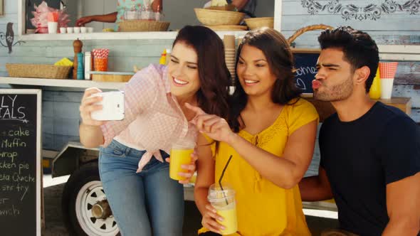 Friends taking selfie from mobile phone in food truck van alt