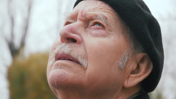 Contemplative old man closing eyes. Close-up face portrait of elderly senior meditating outside alt