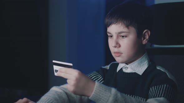 12-13 Year Old Boy Using Computer Laptop and Shopping Online with Credit Card While Sitting at Home alt