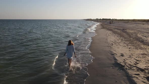 A Girl Walks Along the Water's Edge of a Beautiful Deserted Beach on the Black Sea