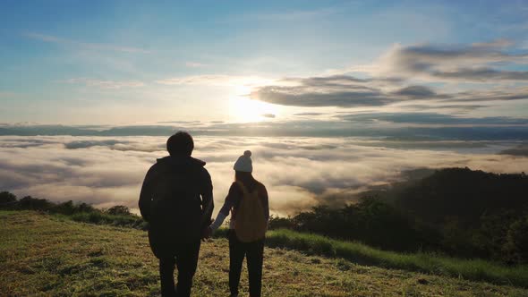 Young couple travelers looking at the sunrise and the sea of mist on the mountain