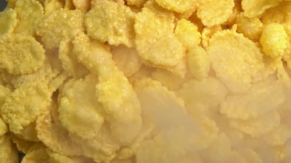 Crispy hot corn flakes rotating with smoke close up, dry healthy breakfast. Honey cornflakes alt