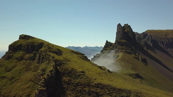 Aerial orbit of verdant steep hill summit, clouds covering mountains in background, in Djúpivogur sm alt