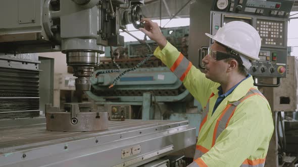 Young asian engineer man working and control machine with system at industrial factory. alt
