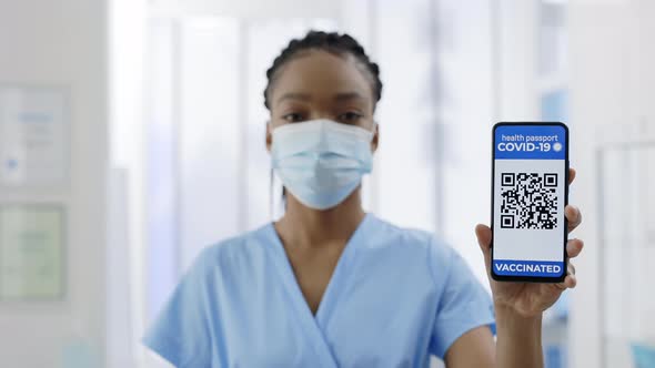 Portrait of Female Doctor Holding Digital Passport of Vaccinated Person alt