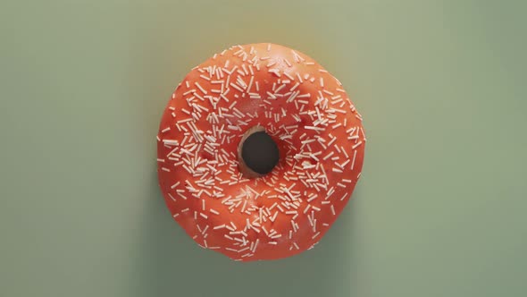 Orange Glazed Donut Rotating on Green Top View