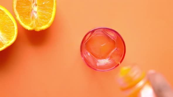 Pouring Orange Juice in Glass on a Color Background alt