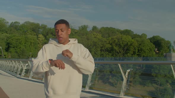 Active Motivated Fit Black Man Checking Tracking Distance on Watch During Jog alt