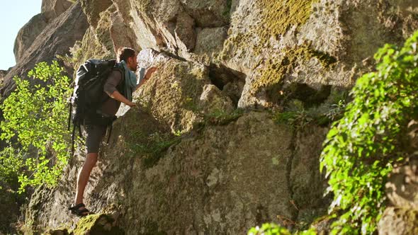 Bearded Caucasian Male in Shorts and Sandales Climbing Up Cliff in Slowmotion alt