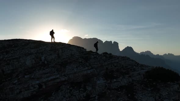 Female and male hikers at the top of the mountain at sunrise. alt