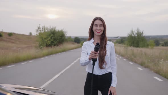 Girl Stands on the Road and Holds the Charger alt