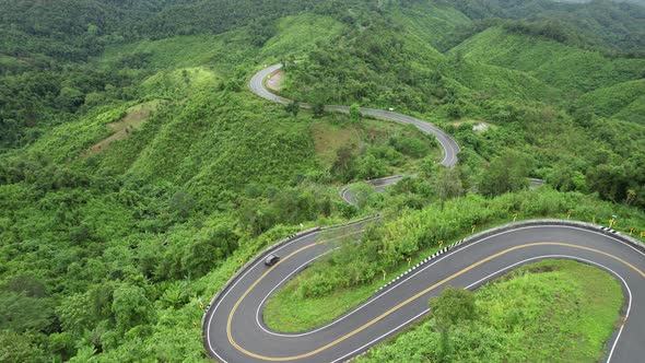 Aerial view of mountain road through tropical forest in countryside of Asia by drone