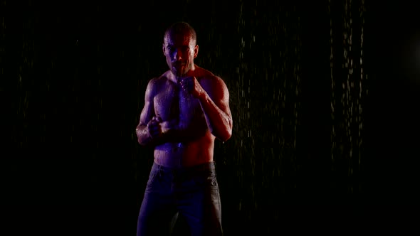 a Muscular Man with a Bare Torso Stands in the Streams of Water on a Dark Background Then Begins to alt