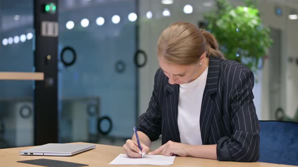 Upset Businesswoman Trying To Write on Paper in Office  alt