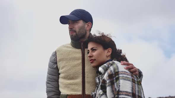 Beautiful Couple Gazing Forward With the Background of the Bright Cloudy Sky alt