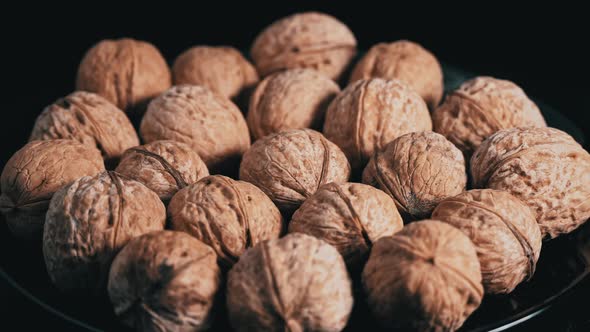 Lot of Walnuts in the Shell are Spinning on a Black Background alt