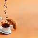 White coffee cup falling on beige table background, splashes, beans, croissant - PhotoDune Item for Sale
