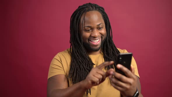 Cheerful AfricanAmerican Man with Dreadlocks Enjoys Spending Time Online alt
