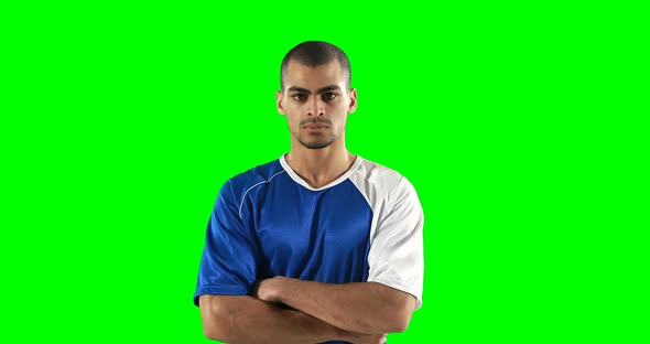 Confident football player standing against green screen alt