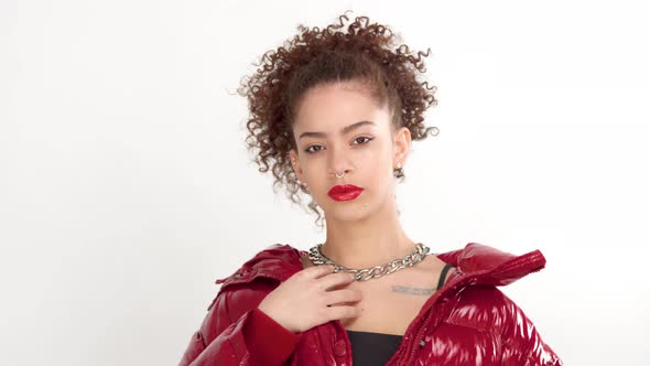 Young Woman with Red Lacquer Lips and Red Shiny Jacket on White in Studio