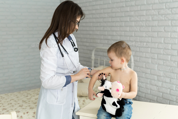 Doctor pediatrician giving child an intramuscular injection in arm ...