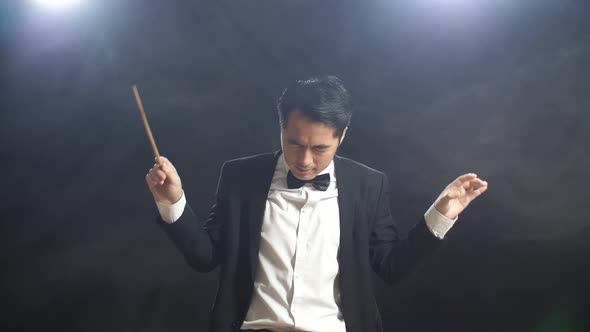Asian Conductor Man Holding A Baton Closing His Eyes And Showing Gesture Quickly In The Black Studio alt