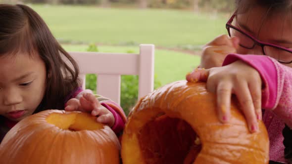 Young girls carving pumpkin for Halloween