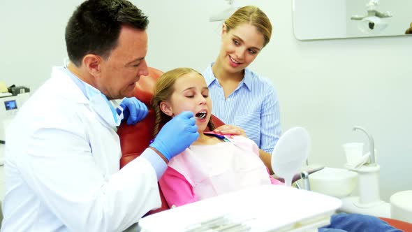 Dentist examining a young patient with tools alt