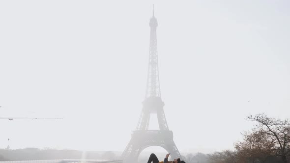 Camera Tilts Down on Paris Eiffel Tower View and Relaxed Happy Male Tourist Lying Down Using alt