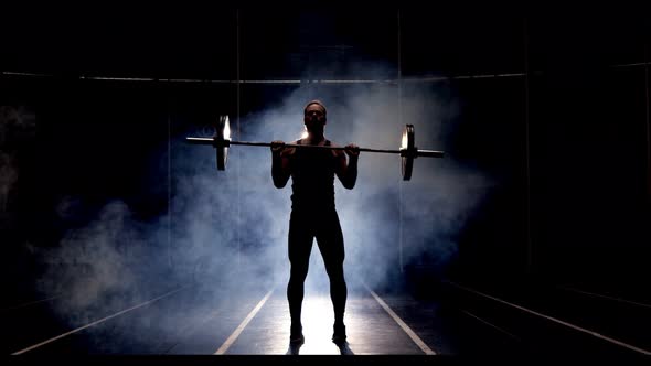 Silhouette of Athletic Man Doing Overhead Deadlift with a Barbell in the Gym