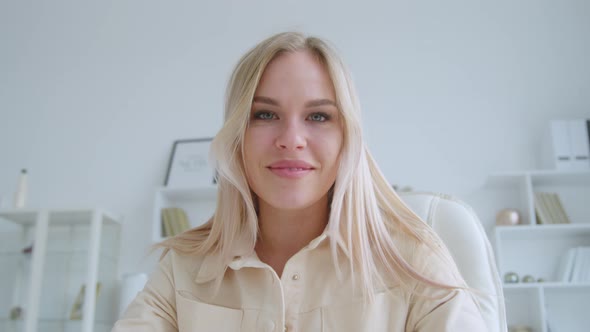 Smiling young woman talking to camera making conference video call alt