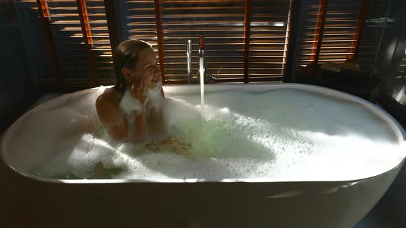 Smiling Sensual Woman Relaxing Take Bath in Bathtub and Playing with Soap Foam alt