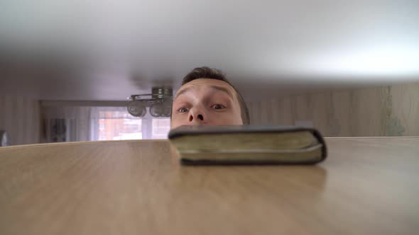 Man Rises High to Ceiling and Places an Old Worn Notebook on Cabinet alt