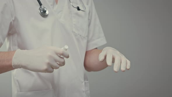 Doctors Gloved Hands He Sprays Antiseptic On His Hands And Rubs Liquid alt