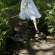 A tranquil moment as a young girl in a white dress wanders through a sunlit garden, crossing - PhotoDune Item for Sale
