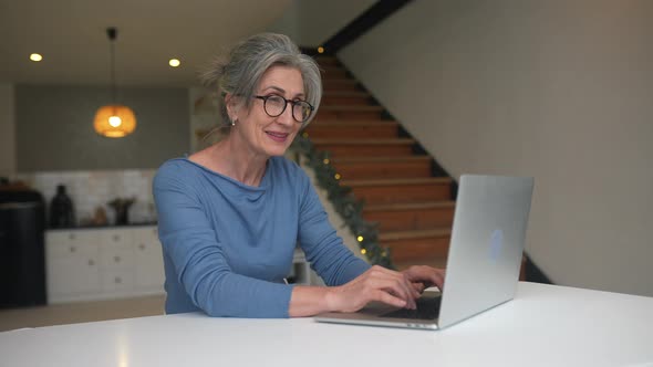 Happy Mature Middle Aged Elderly Woman Looking at Laptop alt