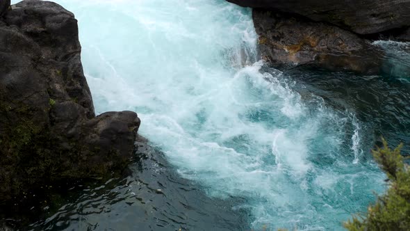 Medium shot of bubbling white water at the vibrant blue Huka Falls in New Zealand. alt