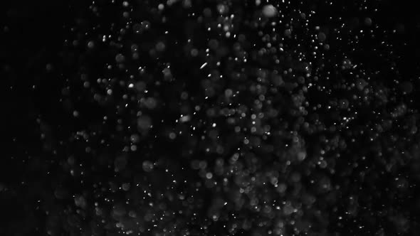 Rising dust particles on black background. Slow motion.