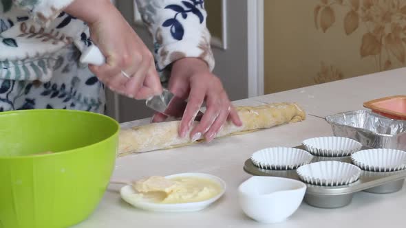 A Woman Cuts A Roll Of Rolled Dough. Prepares Cruffin With Raisins And Candied Fruit alt
