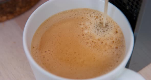 Fresh Hot Coffee is Poured Into the Cup From an Automatic Coffee Machine Forming a Thick Foam on the