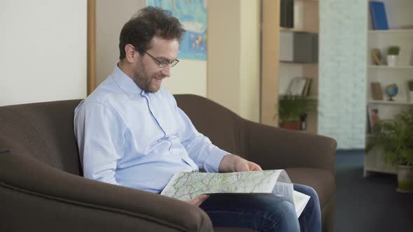 Happy Male Looking at the Map and Planning His Summer Trip, Traveling and Joy alt