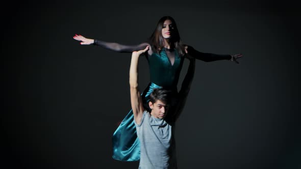 A Couple of Young Dancers Dancing Modern Choreography in the Studio on a Dark Gray Background alt